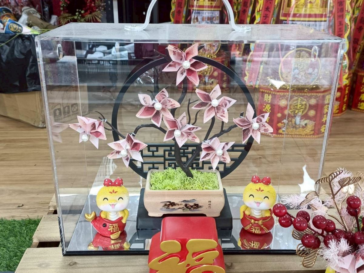 【花的巧思 · 蛇來了】  「蛇來了，蛇來了～來啊來啊蛇來了！」 今年小龍年，花藝師以蛇為靈感， 將百元鈔票摺成精緻花朵，巧妙點綴在作品中。  古色古香的屏風作為背景， 讓每朵鈔票花在其中盛開， 傳統意象與巧思細節交織，營造出自然典雅的氣韻。  蛇象徵財富與智慧，也寓意「帶錢來」。 這樣的花藝不只是美麗的視覺享受， 更是一份悄悄傳遞的祝福。
